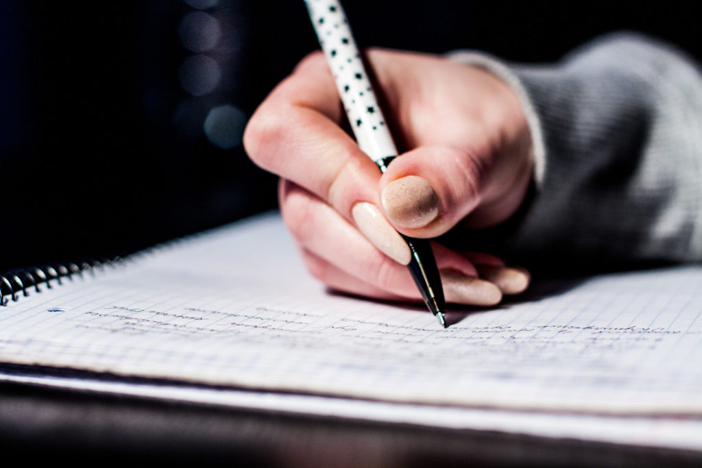 Person writing in journal daily recording events during pandemic